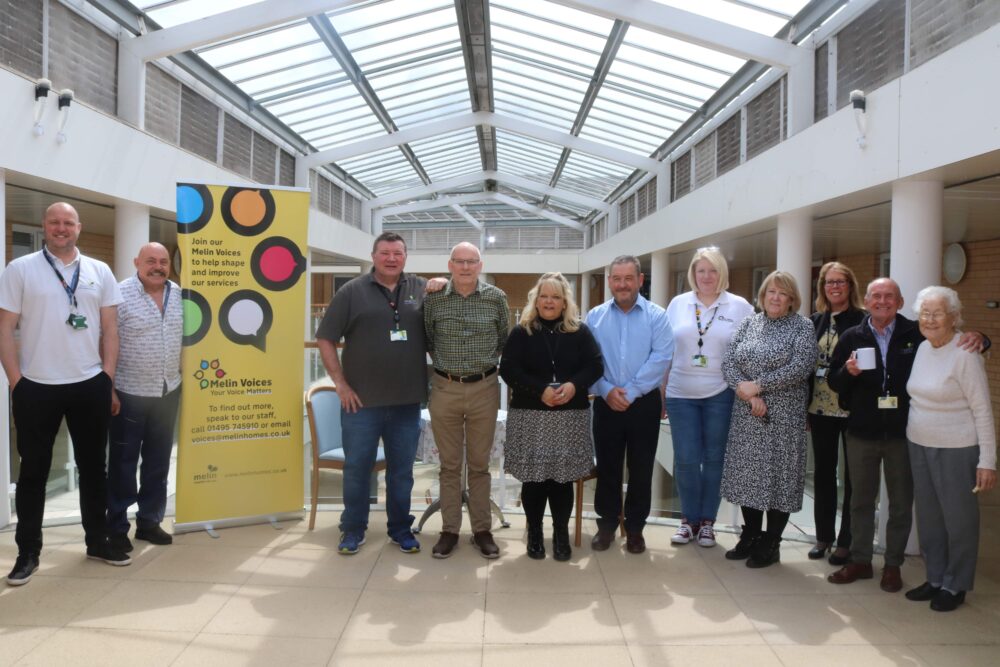 A group of people stood in a line next to a banner with Melin Voices printed on it