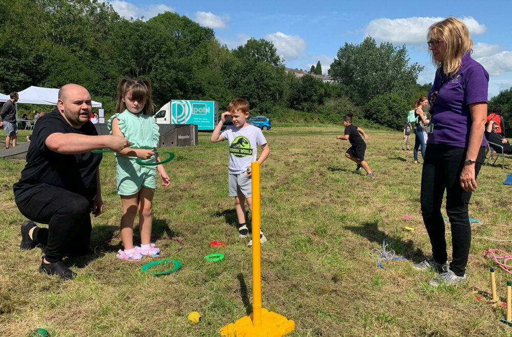 Two members of Melin staff playing games with children on a sunny day