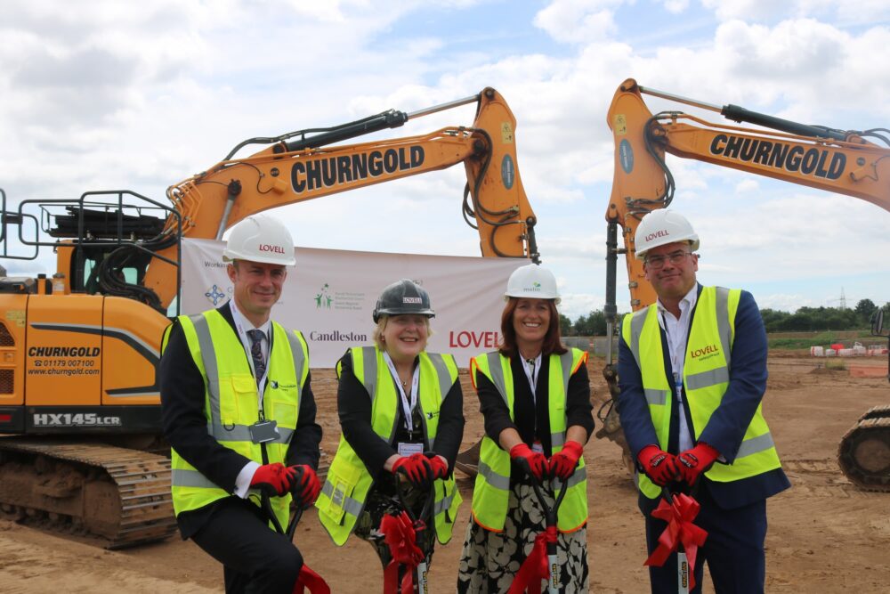 Four people with shovels standing in front of cranes