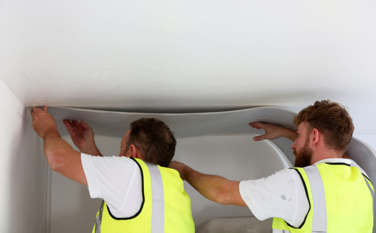 Two of our staff fitting the wallpaper to a ceiling