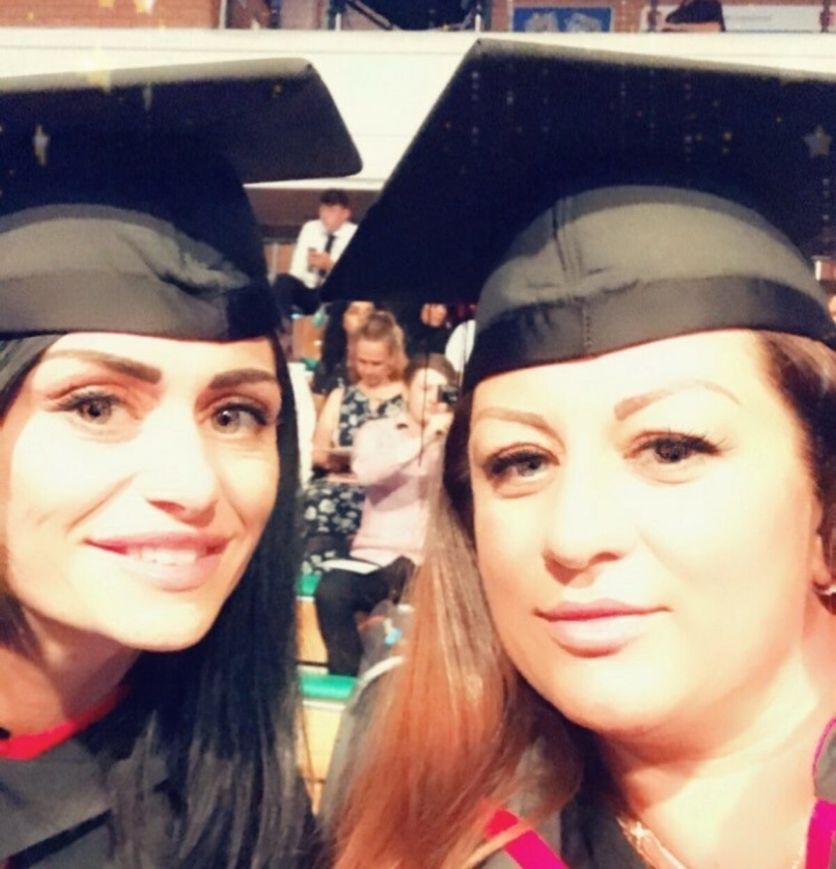 Two women in a selfie style photo wearing a graduation cap and gown