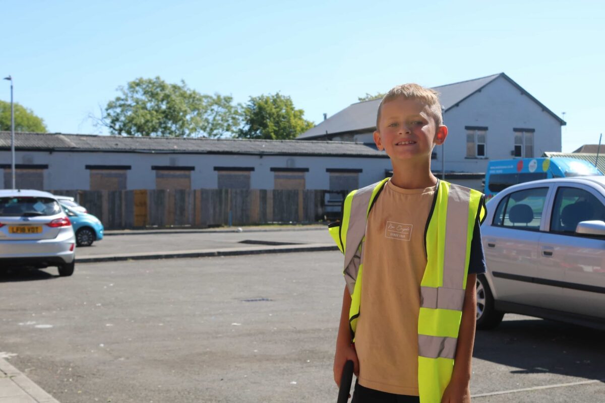 Kian stood in the street wearing a hi-vis vest and holding a litter-picker