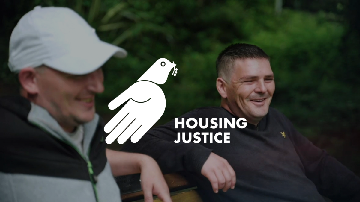 The Housing Justice logo overlaid over an image of two men sat together smiling