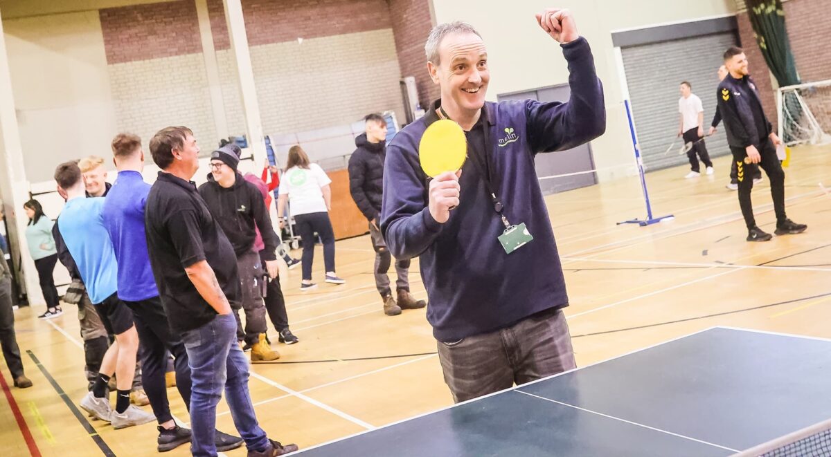 A male Melin staff member celebrating while playing table tennis